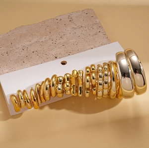 Detail view of gold hoop earring set in various sizes on minimalist stone background