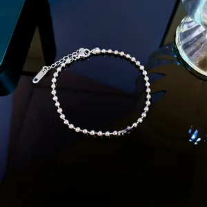 Detailed macro view of stainless steel ball chain bracelet with Elizabeth II coin charm