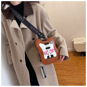 Detail of guitar-shaped crossbody bag with pink wings and star rivets on beige trench coat