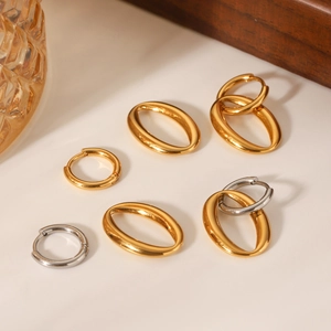 Minimalist oval hoop earrings in gold and silver stainless steel on a soft white surface
