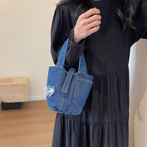 Distressed denim bucket handbag in dark blue with decorative pocket and vintage stitching