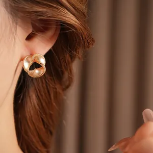Elegant gold twisted stud earrings with pavé crystals and matte finish on a female model