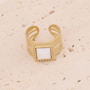 Détail d'une bague multicouche dorée ornée d'une pierre précieuse carrée de couleur blanche