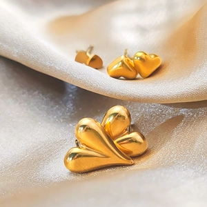 Vue rapprochée de boucles d'oreilles cœur dorées polies sur un tissu de soie champagne