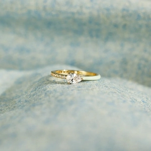 Macro shot of gold pear-cut gemstone ring with mint enamel and pavé diamond details