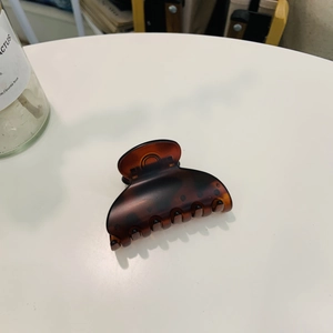 Detail of dark brown tortoiseshell hair claw clip with heart shape on a white surface