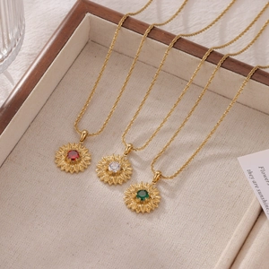 Golden sunflower pendant necklaces with red, green and clear crystals on a tray
