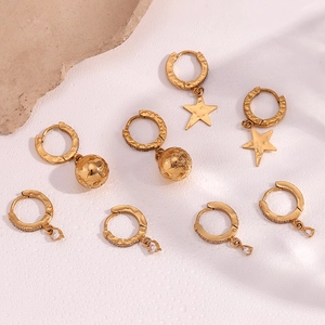 Detail view of 8-piece gold earring set with star and zircon charms on stone prop