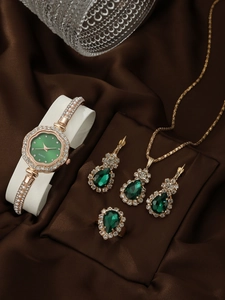 Detailed set of gold watch, green stone necklace, earrings and ring on silk fabric