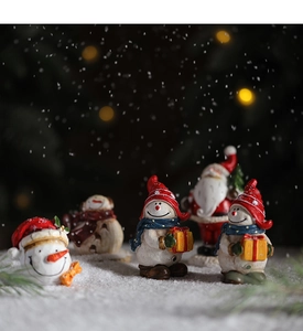 Detailed macro shot of miniature resin Santa Claus and snowman figurines on a desk