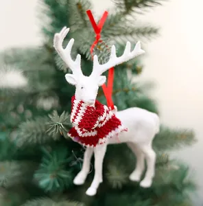 White flocked Christmas reindeer ornament with red striped scarf on green tree branch