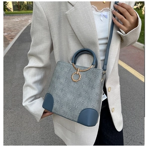Detail of grey bucket bag with blue leather trim and monogram floral pattern textures