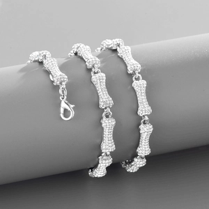 Detailed view of silver bone-shaped hip hop necklace with sparkling crystal inlay