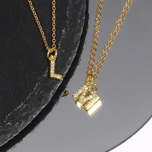 Macro shot of gold-plated letter L and M necklaces with sparkling zircon inlay details