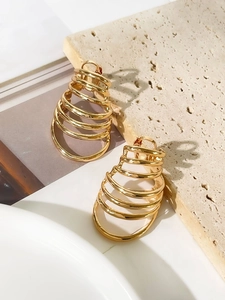 Detailed view of gold multi-layered spiral hoop earrings on a textured stone surface
