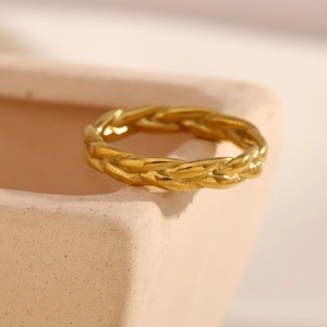 Detailed view of 18K gold plated stainless steel braided ring on ceramic decor