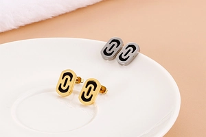 Detailed view of paperclip earrings in gold and silver finish on a ceramic plate