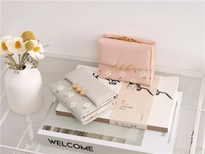 Detailed view of mini floral tri-fold wallets in pink and grey with gold diamond accents