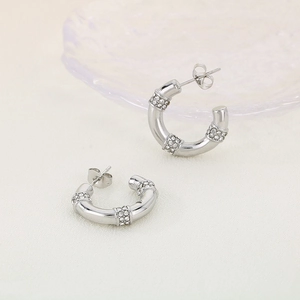 Vue détaillée de boucles d'oreilles C en titane argenté avec trois rangées de zircons blancs