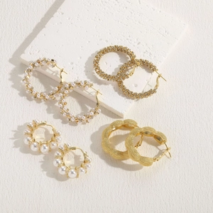 Set of four geometric 14K gold plated earrings with pearls and zircon on stone display