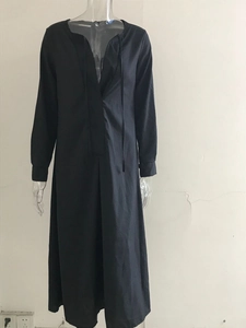 Detalle de vestido largo negro de manga larga con cuello en V y cordones frontales