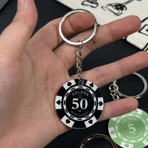 Close-up of black and green casino chip keychains with golden entertainment text