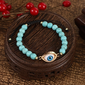 Detail of adjustable evil eye turquoise beaded bracelet on vintage wooden pedestal