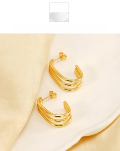 Detail view of 18K gold plated triple layered C-shape earrings on a satin background