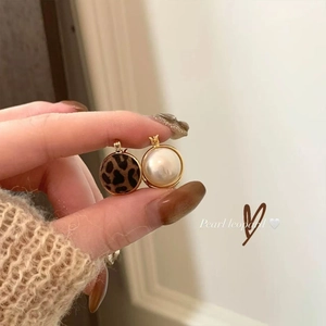 Detail of retro leopard print and white pearl earrings with golden metal frames