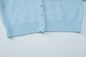 Detail of light blue fuzzy knit cardigan featuring ribbed hem and matching buttons
