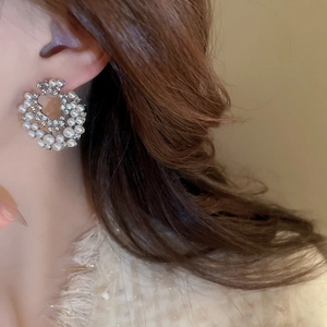 Détails de boucles d'oreilles géométriques avec perles et strass brillants sur l'oreille