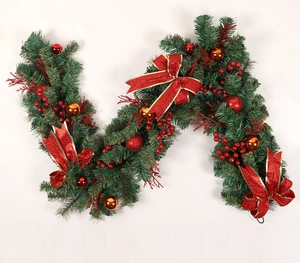 Detail of green Christmas garland with red bows, berries and decorative ornaments