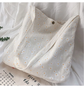 Detail of cream canvas tote bag with daisy floral prints and magnetic button closure