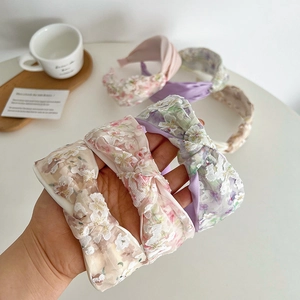 Close-up of floral mesh knotted headbands in beige, pink and purple with 3D embroidery