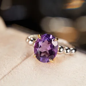 Macro detail of oval purple gemstone set in gold claw on beaded silver ring band
