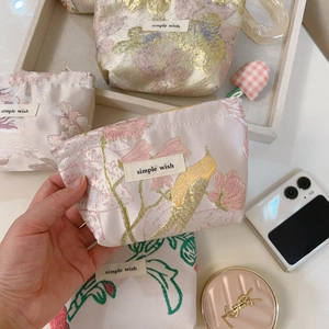 Detailed embroidery of birds and flowers on a pink jacquard fabric mini pouch