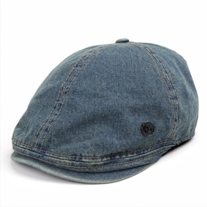 Macro detail of washed blue denim beret with metallic logo and yellow stitching