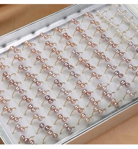 Detailed view of natural freshwater pearl rings in multiple colors arranged in a showcase