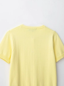 Detail of the light yellow knit top featuring ribbed crew neck and fine texture