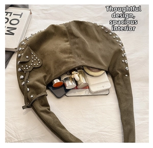 Detail view of the spacious moss green hobo bag with silver studs and heart-shaped pendant