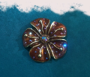 Macro shot of vintage floral brooch with brown enamel petals and sparkling rhinestones