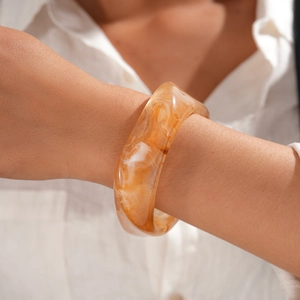Gros plan sur un bracelet en résine ambrée marbrée avec une texture lisse et polie