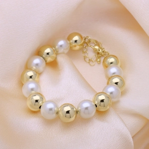 Detail of adjustable pearl and gold bead bracelet with lobster clasp on silk fabric