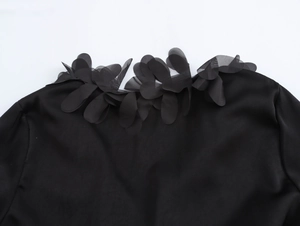 Detail of 3D mesh floral applique on the shoulder of a black elegant V-neck blouse
