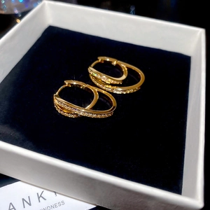 Macro shot of 18k gold plated U-shaped earrings with cubic zirconia in a white gift box
