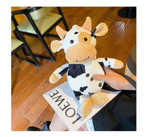 Detail of soft plush cow bag with brown horns and blush cheeks in a cafe setting