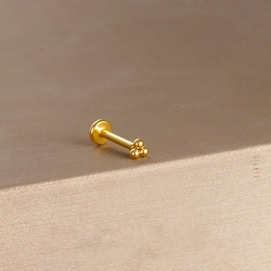 Macro shot of gold trinity bead labret stud featuring three polished beads on flat back post