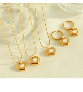 Detail view of heart-shaped shell pendants on gold snake chains and matching earrings