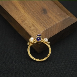 Detailed shot of handmade gold wire-wrapped ring with purple flower and white pearls