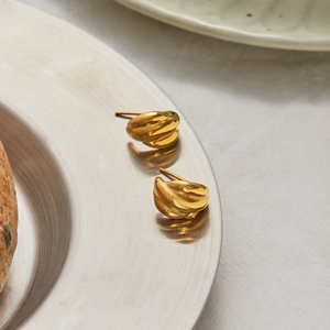 Macro shot of gold triple-layer textured hoop earrings placed on a silver plate